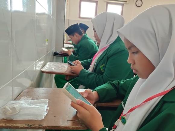 “Siswa MTs Safinda mengikuti ujian online menggunakan handphone”